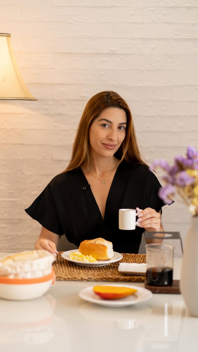 Luiza Diaz, nutricionista, sorrindo à mesa do café da manhã com pão, ovos e café